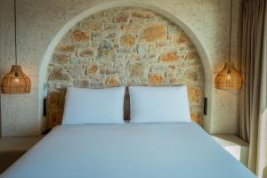 a bed with two pillows in front of a stone wall at Churchill Townhouse in Bodrum City