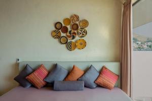 a bed with colorful pillows and a clock on the wall at Churchill Townhouse in Bodrum City