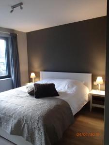 een slaapkamer met een groot wit bed met 2 lampen bij FLY in POPS in Poperinge