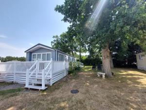 a house with a white fence and a tree at Tulip Lodge at Oakdene - Passes included free! in Ferndown