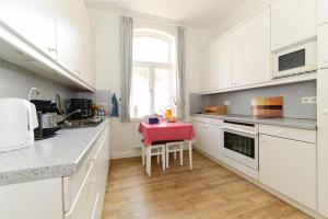 a kitchen with white cabinets and a red table at Pension Hilligenlei Zi 01 EZ in Wyk auf Föhr