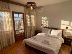 una camera da letto con un letto con lenzuola bianche e una finestra di Villa Hill a Tríkala