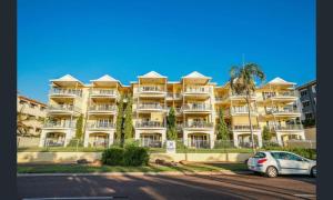 NightcliffSensational Sunsets Ocean Views From Top Floor的一座黄色的大建筑,前面有汽车停放