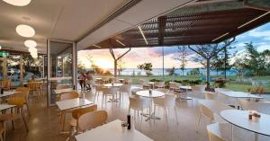 NightcliffSensational Sunsets Ocean Views From Top Floor的餐厅设有白色的桌椅和大窗户