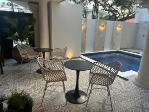 a patio with tables and chairs and a swimming pool at Hotel Boutique Las Mesetas in San Pedro Sula