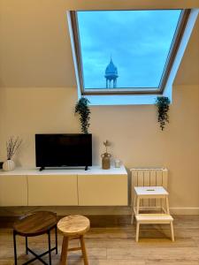 a living room with a tv and a window at Le Petit Jardin, proche gare, hyper centre in Cambrai