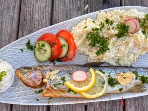 a plate of food with fish and rice and vegetables at Hotel | Restaurant | Forellenzucht in Burgen