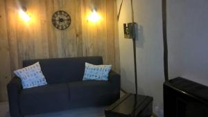 a living room with a couch and a clock on the wall at La Maréchalerie L'ATELIER in Lion-en-Sullias
