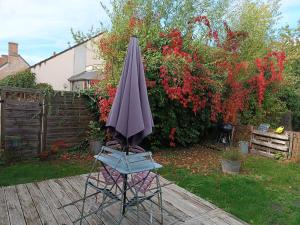a purple umbrella sitting on a chair in a yard at La Maréchalerie L'ATELIER in Lion-en-Sullias