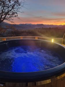 a jacuzzi tub with a sunset in the background at Le refuge des Toupins in Prunières