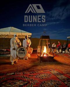 a group of people standing next to a fire at Dunes Berber Camp in Merzouga