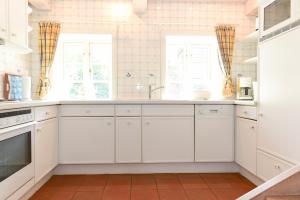 a white kitchen with white cabinets and windows at Faskers Hüs Whg 02 in Oldsum