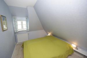 a small room with a yellow bed in a attic at Faskers Hüs Whg 02 in Oldsum
