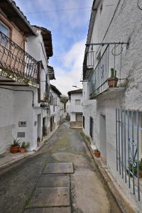 an alley with white buildings and potted plants at 'La Casa de LoLa' casita de cuento con vistas in Arenas de San Pedro