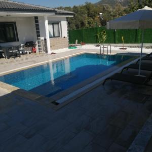 a swimming pool in a yard with an umbrella at Airport Doğa evleri in Dalaman