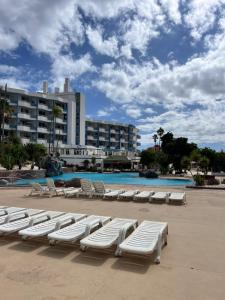 a row of white lounge chairs on a beach at Golf del Sur GreenPark apartments with pool Corbeta 118 in San Miguel de Abona