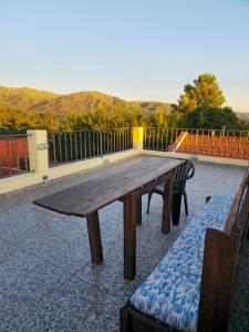 a wooden picnic table with a bench and mountains in the background at Posada Spa Anabela in Huerta Grande