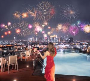 Eine Frau steht am Rande eines Daches mit Feuerwerk in der Unterkunft Golden Sands Boutique Hotel-Dubai Creek in Dubai