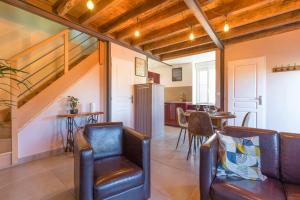 a living room with leather chairs and a kitchen at L Atelier du Marcel in Meilly-sur-Rouvres