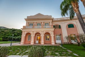 a large pink house with a palm tree at Villa Irlanda Grand Hotel in Gaeta