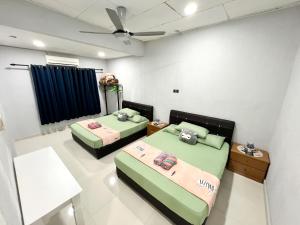 a room with two beds and a ceiling fan at Sehijau Homestay Taman Ira in Kangar
