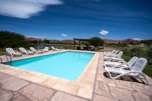 a swimming pool with white chairs and a bunch ofitures at Hotel Castillos de Cafayate in Cafayate