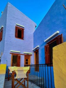 a white house with red windows and a bench in front at Symi Uptown Indigo in Symi