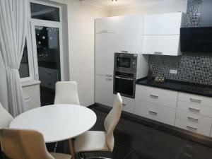 a white kitchen with a white table and chairs at Сучасна квартира в ЖК Friendly House in Kyiv