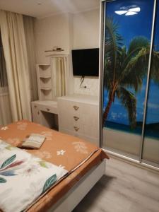 a bedroom with a bed and a window with a television at Сучасна квартира в ЖК Friendly House in Kyiv