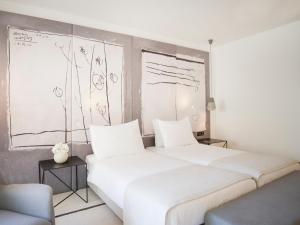 a bedroom with a large white bed and drawings on the wall at Hotel Kompas in Dubrovnik