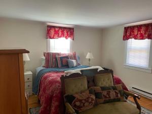 a bedroom with a bed and a chair and windows at The Hideaway in Brewster