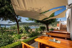 a wooden table with a umbrella and a bench at Apartments Marija in Supetarska Draga