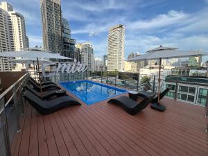 a rooftop deck with a swimming pool and umbrellas at Emiri Hotel - Nana Bangkok in Bangkok