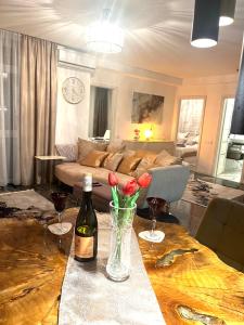 a living room with a table with a bottle of wine and flowers at Violet Superior in Nyíregyháza