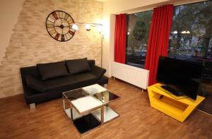 ein Wohnzimmer mit einem schwarzen Sofa und einem TV in der Unterkunft Art City Studio Kassel in Kassel