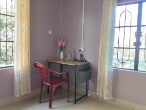 a table and a chair in a room with windows at Ajem-Lar Homestay in Dimapur