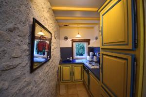 a small kitchen with yellow cabinets and a window at Maison à Sauvagnas avec piscine - Clévacances 3 clés in Sauvagnas