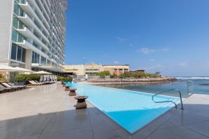a swimming pool next to a large building at Terrado Suites Antofagasta in Antofagasta