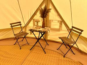 波特拉什North Coast Glamping - The Open 2025的帐篷内的2把椅子和1张桌子