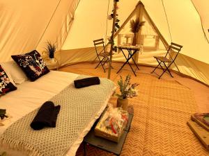 波特拉什North Coast Glamping - The Open 2025的帐篷配有一张床和一张桌子及椅子 更多16张照片