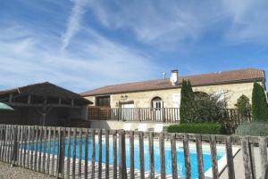 a house with a fence next to a swimming pool at Maison ancienne à Puymiclan - Clévacances 3 clés in Puymiclan