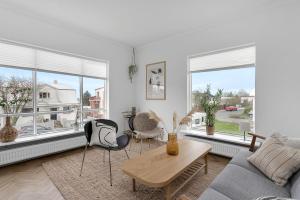 a living room with a couch and chairs and windows at Lovely & Spacious Apartments in Reykjavík
