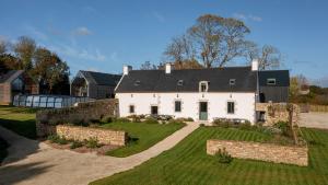 a large white house with a stone wall at Villas Goarem Louzet in Tréméoc