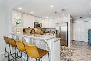 a kitchen with white cabinets and a bar with stools at Emerald Isle Gulf Front 2B Condo - 1604 in Pensacola Beach
