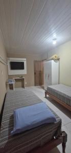 una camera da letto con due letti e una TV a schermo piatto di Casa Celeste a Boa Vista
