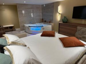 a bedroom with a large white bed and a tub at Spa Suite Vichy LOFT in Vichy