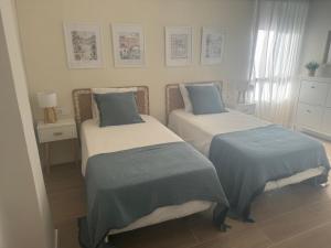 a bedroom with two beds with blue pillows at Ca Maruja in Cullera