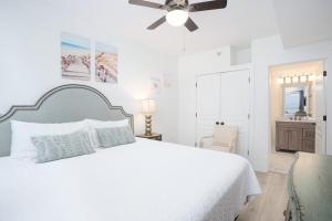 a bedroom with a white bed and a ceiling fan at Emerald Isle Gulf Front 2B Condo - 805 in Pensacola Beach +19 photos
