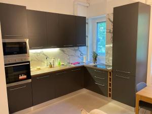 una cucina con armadi neri e una finestra di Apartment in Affori a Milano Altre 11 foto