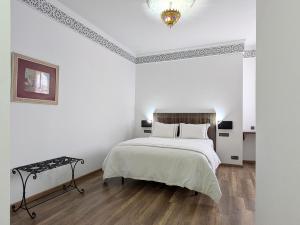 a white bedroom with a large bed and a chandelier at Hôtel Les Remparts in Azemmour +59 photos